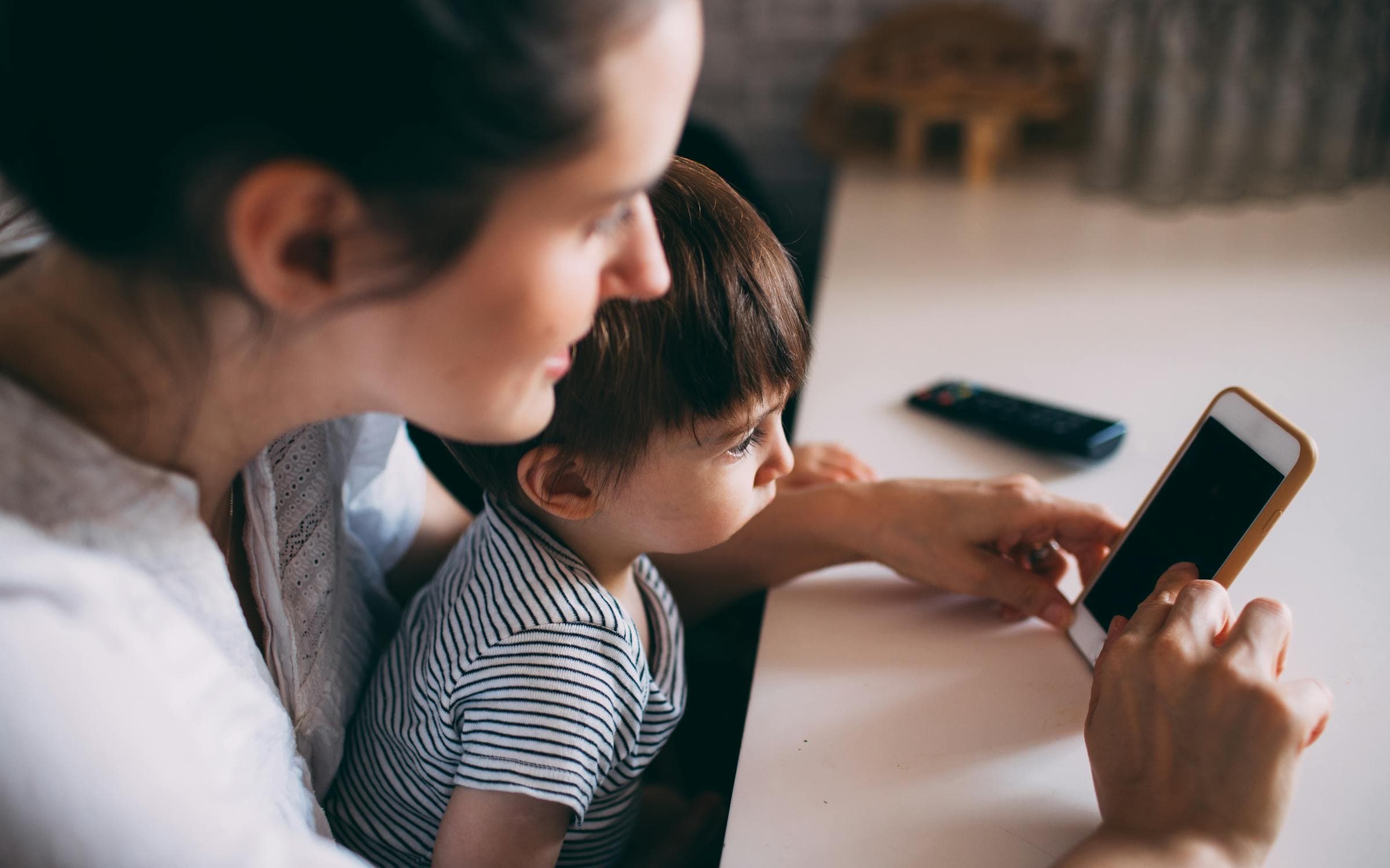 A parent and child looking at a phone together at home.