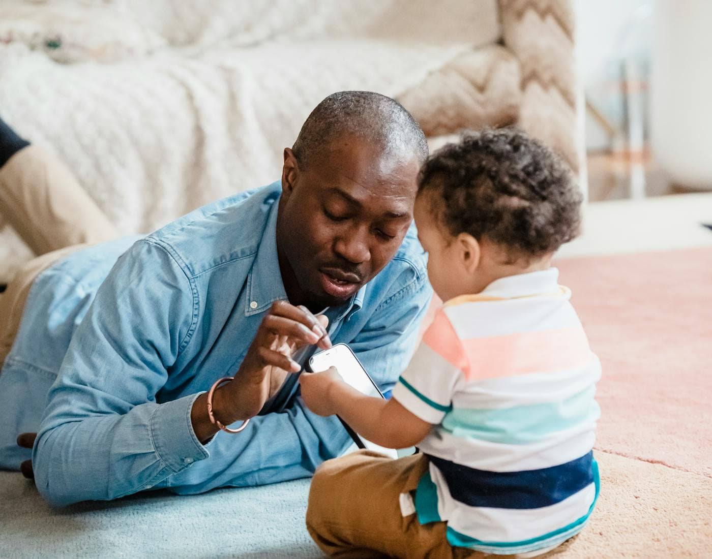 A parent guiding a child through phone practice at home.